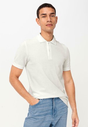 Lichtgrijze polo hemd, korte mouwen, kraag, met knoopsluiting van drie knopen. Draagbaar met lichtblauwe jeans, gladde stof met een subtiele textuur.