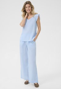 Set da pigiama a righe blu chiaro composto da una maglietta con scollatura a V e maniche a volant, e pantaloni a gamba larga. Tessuto morbido con tasche per il massimo comfort.