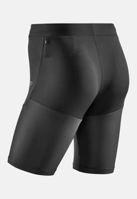 Schwarze Sportshorts mit einem glatten oberen Bereich und einem strukturierten, meshlike unteren Bereich. Enthält eine Rückentasche mit Reißverschluss zur Aufbewahrung.