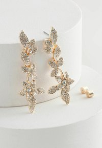 Zlatne naušnice s cvjetnim uzorkom, ukrašene prozirnim rhinestones. Sadrže uzorak lista, montirane na post.