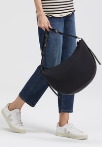 Schwarze Nylon-Crossbody-Tasche mit runder Form, verstellbarem Riemen und Reißverschluss. Verfügt über eine glatte Textur und ein minimalistisches Design.
