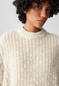 Maglione bianco a maglia grossa con un alto collo a costine e un motivo testurizzato. Realizzato in filato morbido con un aspetto accogliente.
