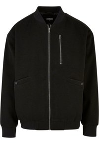 Chaqueta bomber negra con cremallera frontal, dos bolsillos laterales y puños acanalados. Confeccionada en un tejido suave con un diseño limpio y minimalista.
