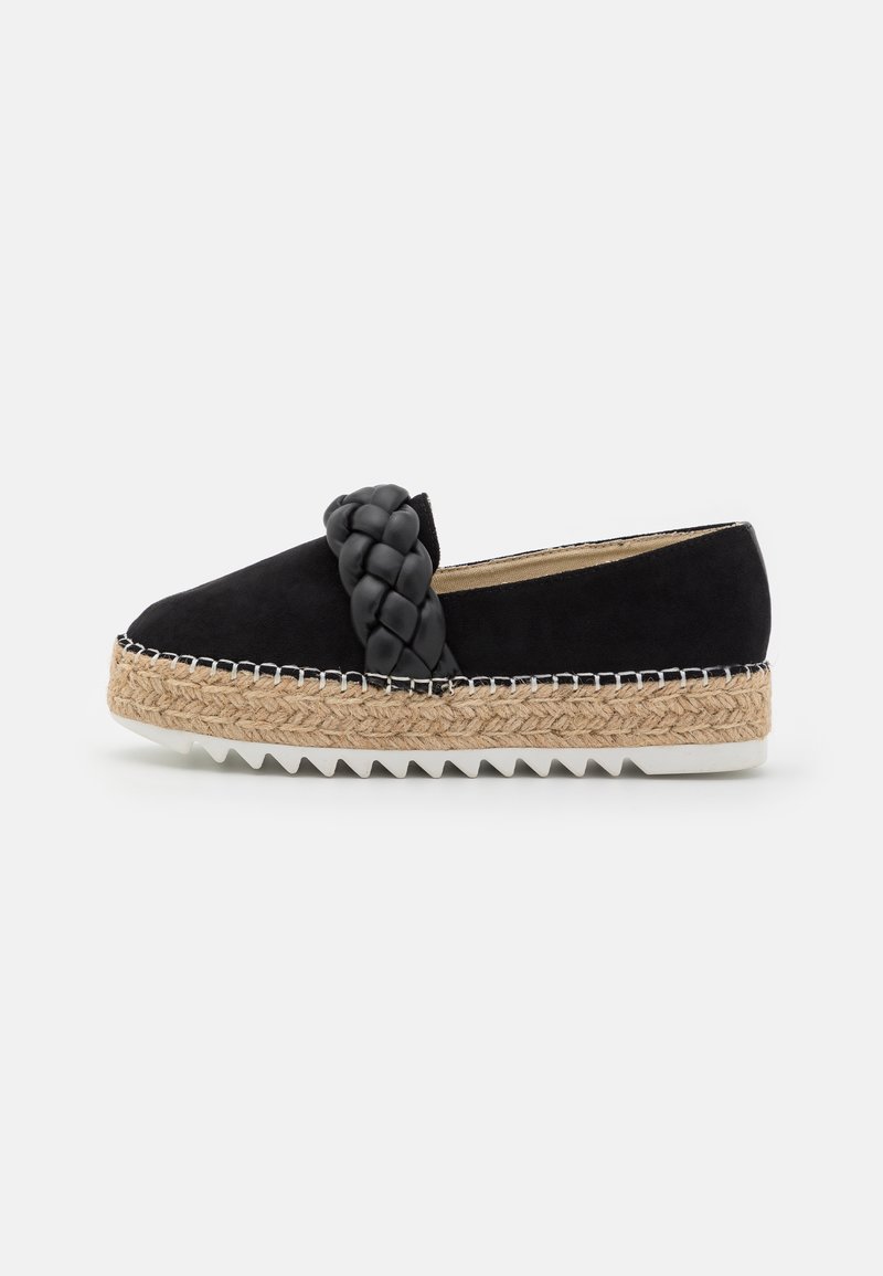 Espadrille noire à enfiler avec une sangle tressée, une semelle plateforme en jute tissé, et une semelle extérieure en caoutchouc blanche à motif zigzag.