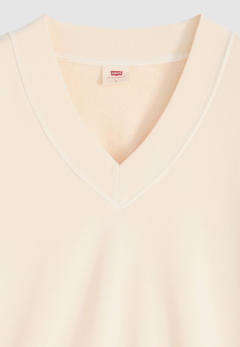Pull col en V couleur crème avec col côtelé et étiquette de la marque Levi's à l'intérieur du col, taille petite.