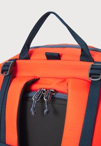 Mochila naranja con un patrón de cuadrícula texturizado, correas azul marino, doble cremallera y un exterior de tela duradera. Presenta un asa robusta.