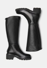 Botas de cuero negras hasta la rodilla con un tacón grueso, acabado texturizado, cremallera lateral y costuras definidas sobre una superficie lisa.