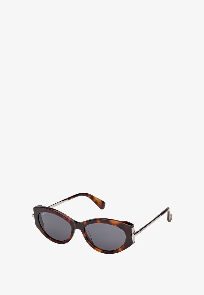 Occhiali da sole a forma di occhio di gatto in tartaruga, con lenti scure e sottili bracci in metallo, su uno sfondo bianco.