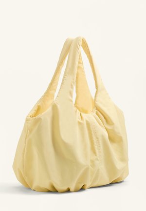 Měkká, polstrovaná světle žlutá taška přes rameno se staženou textilií a širokými držadly, zobrazena na jednobarevném světlém pozadí.
