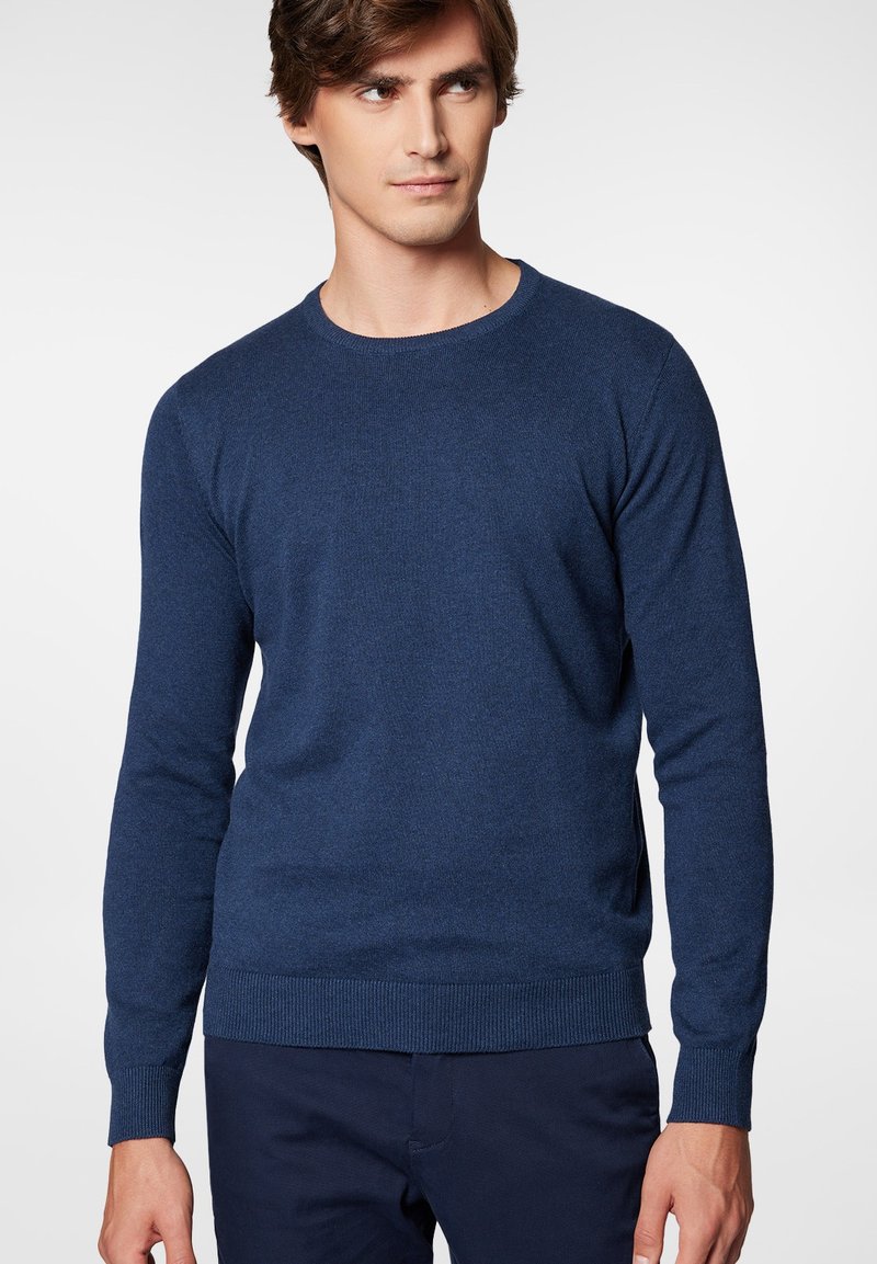 Granatowy sweter dzianinowy z okrągłym dekoltem i długimi rękawami. Posiada ściągacze na dole i na mankietach, wykonany z miękkiego, teksturowanego materiału.