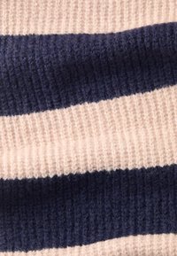 Strikket stof i skiftende striber af blød beige og mørkeblå, med et tekstureret, ribbet mønster og synlige fibre.