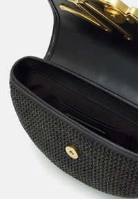 Černá kabelka s tkanou texturou; vnitřek obsahuje hladkou kůži a látku se sloty na karty; zlaté kování na zapínání.