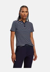 Granatowa i biała w paski koszulka polo z krótkim rękawem, z kołnierzykiem i listwą guzikową. Wykonana z gładkiego, miękkiego materiału, który ładnie układa się na ciele.