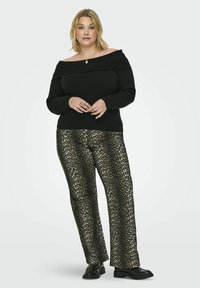 Zwarte off-the-shoulder gebreide trui gecombineerd met een wijde broek met luipaardprint en zwarte schoenen. Gelaagd stof en gedurfde dierenprint.