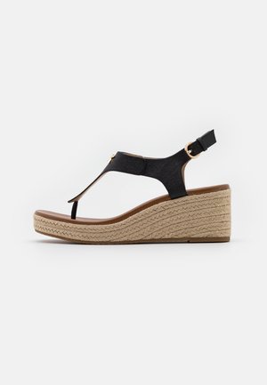 Sandale compensée en tissu noir avec design à bride en T, compensée enveloppée de jute, bride de cheville ajustable et détail subtil en métal doré.