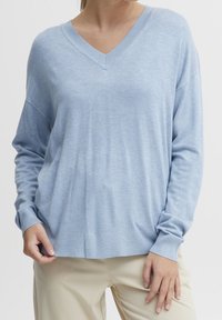 Hellbblaues V-Ausschnitt-Strickpullover mit langen Ärmeln, gerippten Bündchen und Saum. Weiche Textur mit lockerer Passform und lässigem Stil.