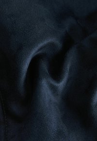 Textil suave en un oscuro tono marino con una textura lisa, que presenta un brillo sutil y suaves pliegues, destacando una forma elegante y fluida.