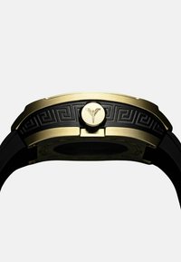 Gouden en zwarte horloge met een gepatineerde bezel, ronde wijzerplaat en een gouden drukknop. De band is gemaakt van zwart rubber voor duurzaamheid.