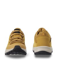 Zapatillas deportivas amarillas con exterior de tela texturizada, punta redondeada y suela de goma con un agarre estampado; logotipo negro contrastante en la lengüeta.
