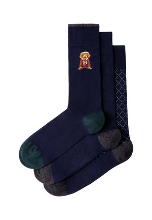 Drei Paar dunkelblaue Socken mit unterschiedlichen Farben an Zeh und Ferse; eines hat einen kleinen Bären mit einem rot gestreiften Pullover und einem "H" am Bündchen.