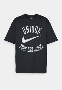 Sort t-shirt i sort bomuldsmateriale med hvid tekst "UNIQUE TOUS LES JOURS" og et sølvfarvet Nike-logo. Klassisk rund halsudskæring og design med korte ærmer.