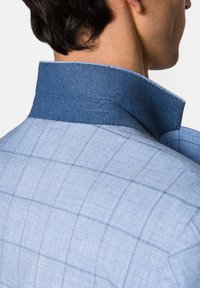 Light blue shirt featuring a textured, checkered pattern with a contrasting dark blue collar. Tailored fit, showcasing a structured design.