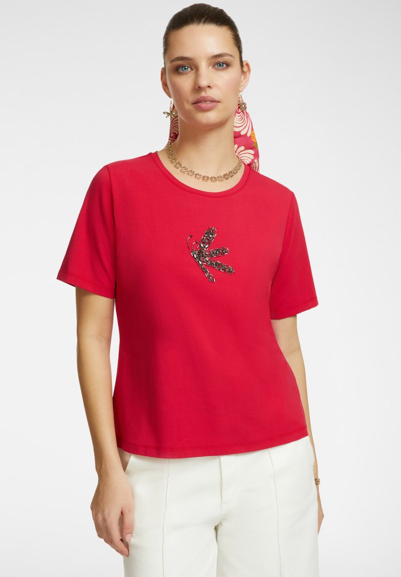 Maglietta di cotone rossa con maniche corte, caratterizzata da un design di insetto ricamato nero e colorato sulla parte anteriore. Vestibilità casual e scollo rotondo.