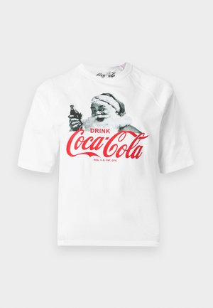 Tricou alb cu un Moș Crăciun vintage ținând o sticlă de Coca-Cola și textul roșu "Drink Coca-Cola" pe față.