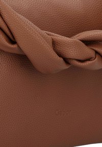 Braune Leder-Clutch mit einer strukturierten Oberfläche, die ein geknotetes Akzent auf dem Deckel aufweist. Dezentes eingeprägtes Logo am Boden.