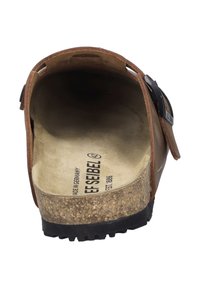 Sándal de cuero marrón con plantilla de corcho. Presenta una correa con hebilla y una suela de goma texturizada. El interior muestra detalles de la marca.