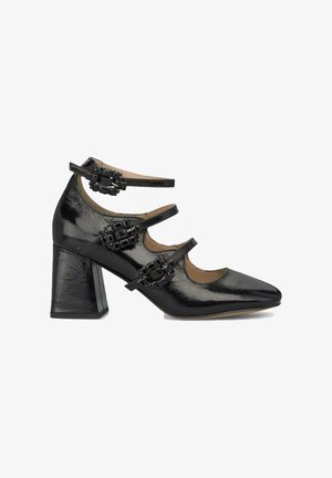 Chaussures à talons hauts en cuir verni noir avec un bout pointu et trois brides réglables ornées de décorations noires.