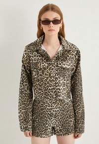 Denimjakke og shorts sæt med leopardprint, stor krave, knaplukning og forlommer. Teksturstof i nuancer af brun og sort.
