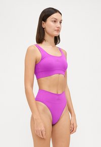 Magenta športni kratki top in visokotlačne spodnje hlačke iz gladkega, raztegljivega materiala z diskretnim logotipom na sprednji strani.