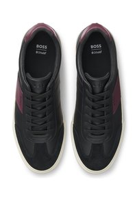 Črni usnjeni supergi z burgundskimi poudarki, teksturiranimi paneli, okroglim sprednjim delom in črnimi vezalkami. Imajo belo podplat in oznake na notranji strani.