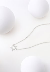 Silver kedja med ett stjärnformat hänge. Hänget är tunt, konturerat och hänger från en delikat, länkad kedja.