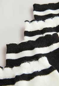 Gestreepte sokken met afwisselend zwarte en witte horizontale strepen, voorzien van een geribbelde textuur en een scalloped bovenrand.