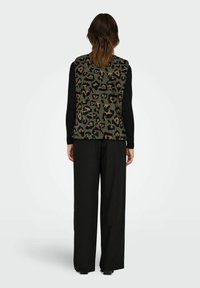 Gebreid vest in olijfgroen met luipaardpatroon, gecombineerd met lange zwarte mouwen en losse zwarte broek. Gladde textuur, casual pasvorm.