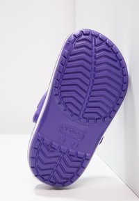 Suola di scarpa in gomma viola con pattern testurizzati per una presa migliore e forma arrotondata, dotata di un bordo bianco e logo impresso.