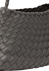 Grå vävd läderväska med ett texturerat, gallerliknande mönster och rundad form, utrustad med en bekväm axelrem.