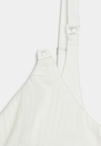 Valge ribaline bralette, millel on sujuv disain, reguleeritavad rihmad ja ühel rihmal plastist konksulukk kindla sobivuse tagamiseks.