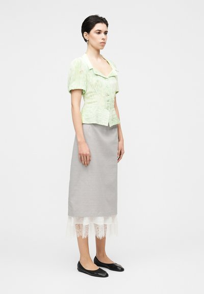 Ανοιχτό πράσινο μπλουζάκι με κοντά μανίκια, γιακά και υφασμένο σχέδιο, συνδυασμένο με γκρι μίντι φούστα-μολύβι με λευκή δαντέλα στην άκρη και μαύρες μπαλαρίνες.