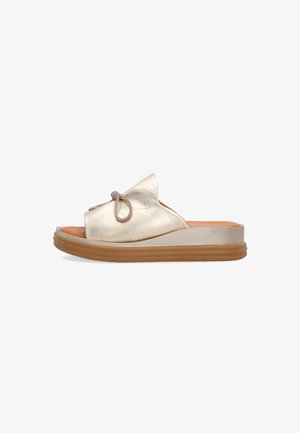 Slip-on sandal med metallic gylden overdel, dekorativ sløjfe, tyk beige sål og tanfarvet gummiydersål, vist fra siden.