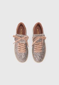 Zapatillas brillantes en color rosa dorado con un acabado texturizado, cordones beige y un interior sutil en tono marrón. Suela de goma y acentos suaves.