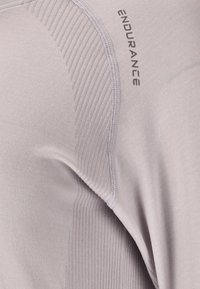 Hellgraues Sportshirt mit gerippter Textur, glattem Stoff und "ENDURANCE"-Logo. Verfügt über ein stromlinienförmiges Design und flache Nähte.