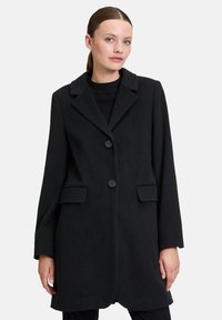 Schwarzer Wollmantel mit Reverskragen, zwei vorderen Taschen und zwei Knopfverschlüssen; zeichnet sich durch eine glatte Textur und eine maßgeschneiderte Passform aus.