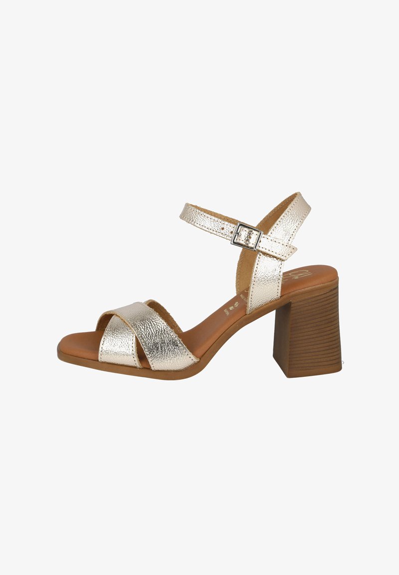 Sandalias de tacón doradas metálicas con un acabado texturizado, que presentan dos correas anchas en la parte delantera y una correa en el tobillo ajustable. Tacón cuadrado marrón.