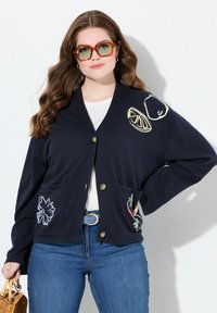 Marinblå cardigan med två frontfickor, prydd med broderi av en citron, en päron och blommönster. Tillverkad av mjukt tyg med avslappnad passform.