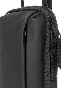 Busta nera con zip realizzata in materiale testurizzato. Presenta una superficie liscia, dettagli cuciti e una robusta tracolla in nylon.