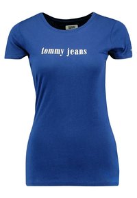 Blå bomullströja med korta ärmar och rund halsringning, med "tommy jeans" tryckt i vitt över bröstet. Slät yta.