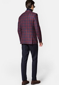 Kraciasty blezer w burgundzie i granacie, z kołnierzem typu notch i dopasowanym krojem, zestawiony z granatowymi spodniami i brązowymi butami.